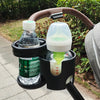 Schwarze Kinderwagen-Tasse und Handyhalter mit braunem Lederriemen, die eine Wasserflasche und ein Glas Flüssigkeit halten.