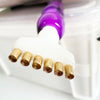 A close-up of a diamond painting pen set with interchangeable gold tips and a purple pen tip resting on a white surface.