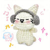 A handmade white crochet kitten plush toy with gray ears and facial markings, surrounded by musical notes.