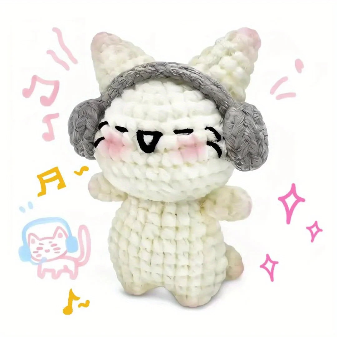 A handmade white crochet kitten plush toy with gray ears and facial markings, surrounded by musical notes.