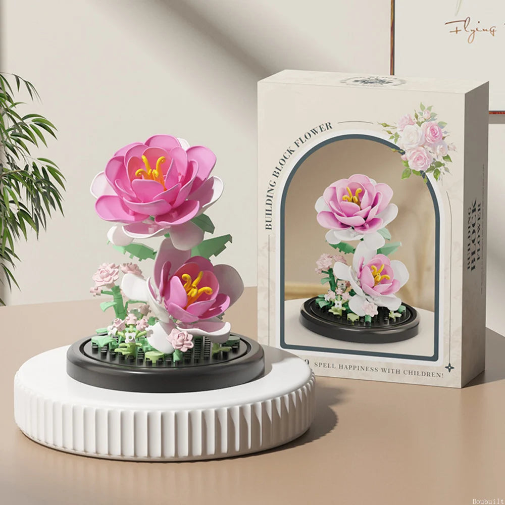 A white box displaying a pink eternal flower garden made of micro building blocks with a dust cover.