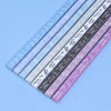 A collection of 27 assorted colored origami star strips laid out diagonally on a light blue surface.