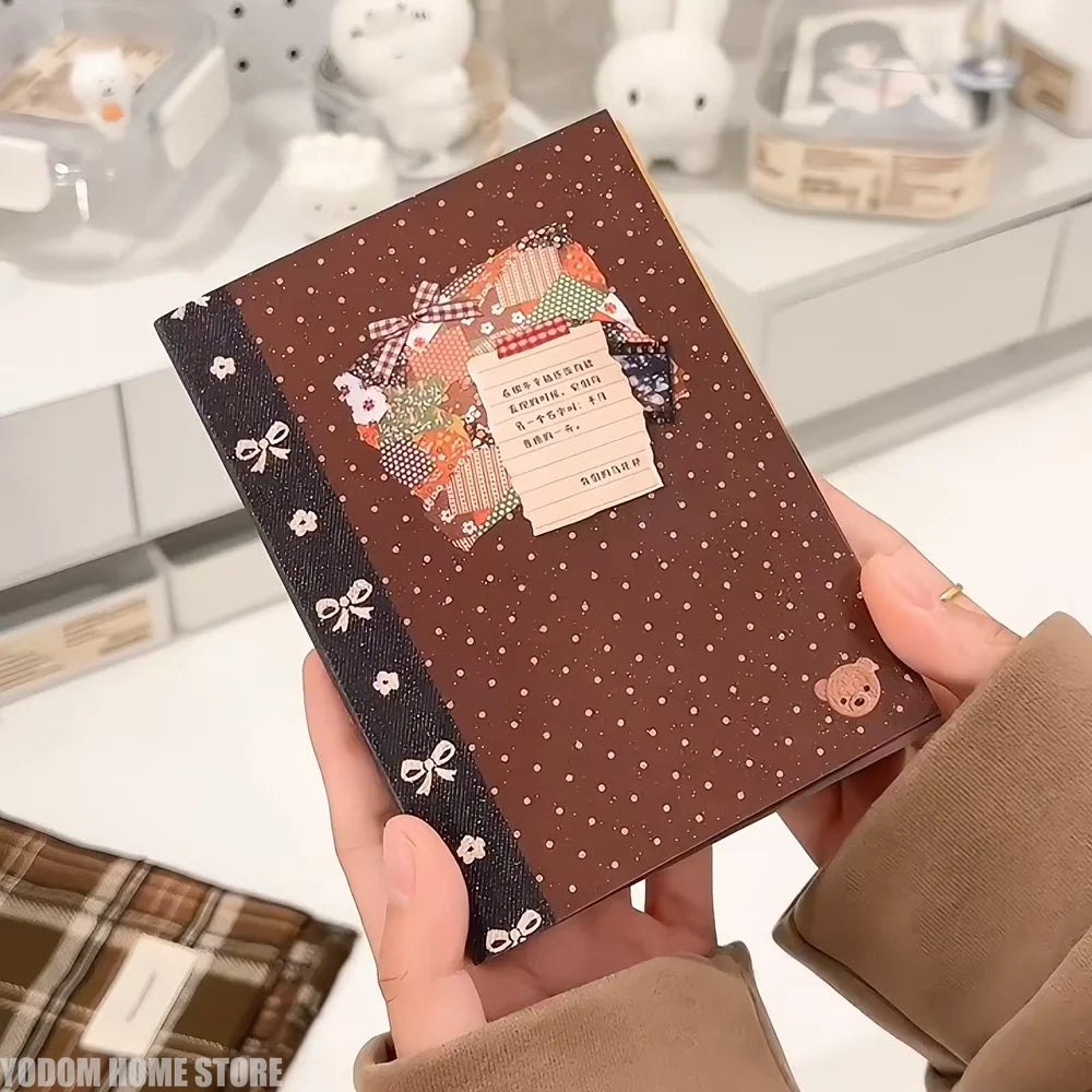 A brown sticker book with decorative elements and a small tag is held in a person's hand.