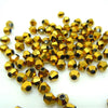 A pile of small, faceted glass bicone beads in a golden amber color for jewelry making.