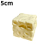 A pale yellow, squishy cheese cube stress ball with visible holes.