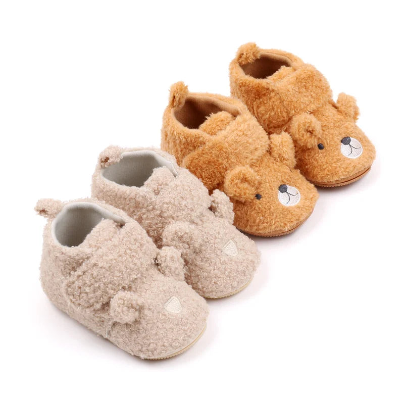 A set of three adorable bear-themed baby prewalker shoes in soft brown and beige fuzzy material.