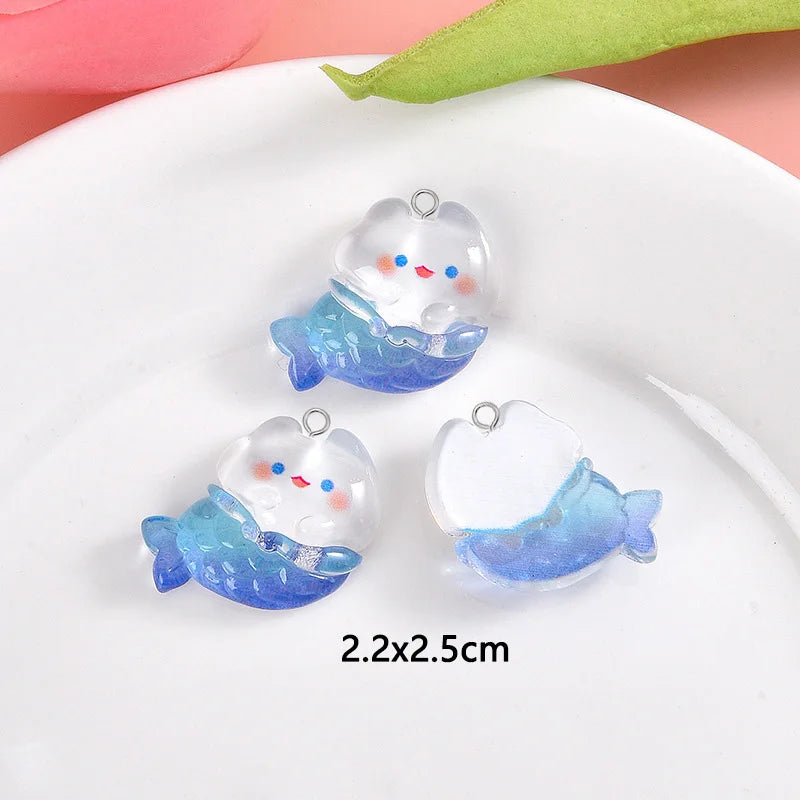 Three clear resin charms shaped like smiling blue fish with white accents on a white plate