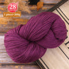 A ball of deep purple yarn is shown on a wooden surface, with a color code label nearby.