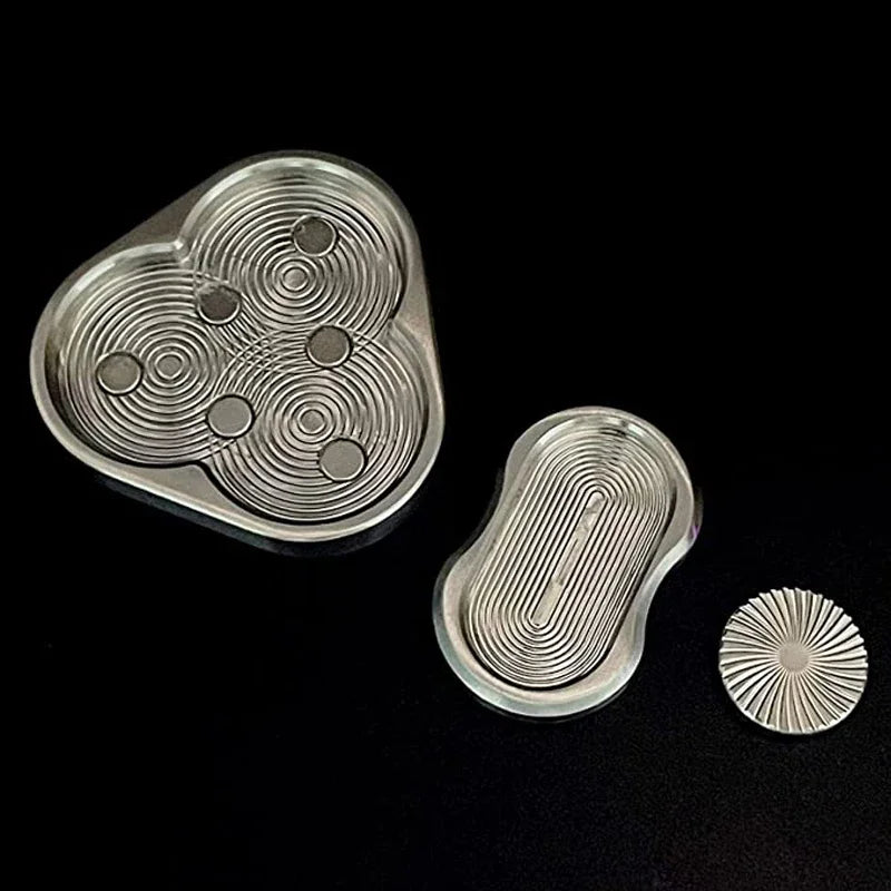 A silver metal fidget slider with concentric grooves and a circular disc is shown against a black background.