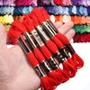 A hand holds several skeins of vibrant red embroidery thread for cross stitch and DIY crafts.