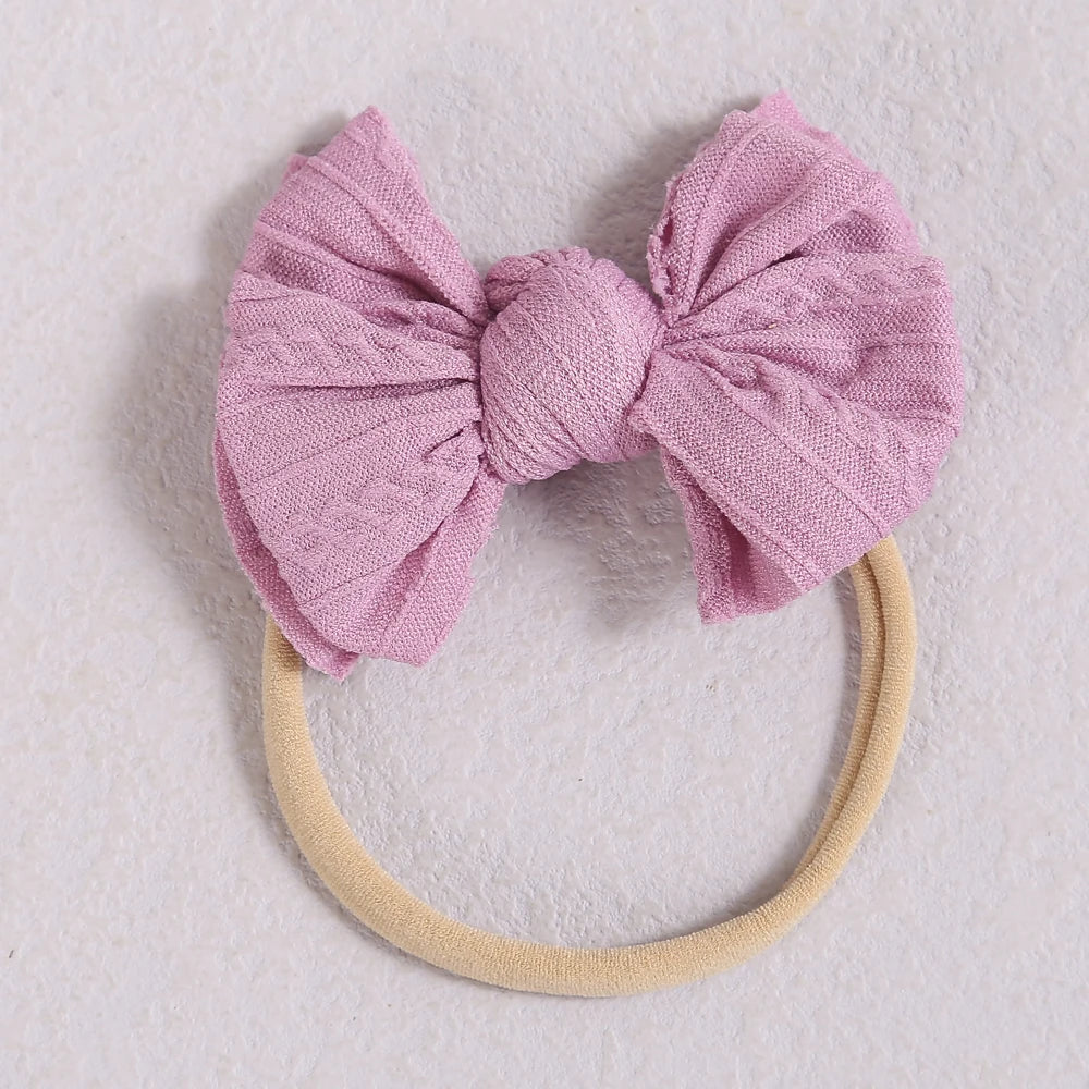 A light pink fabric bow headband with a beige elastic band, suitable for a baby or girl.