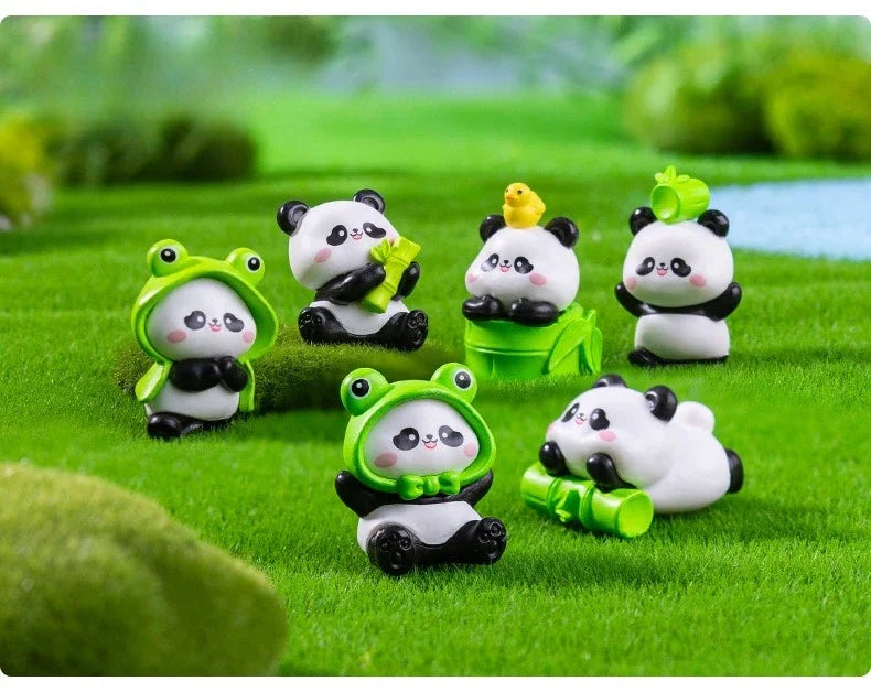 A set of adorable resin panda figurines in various colors sitting on green grass.