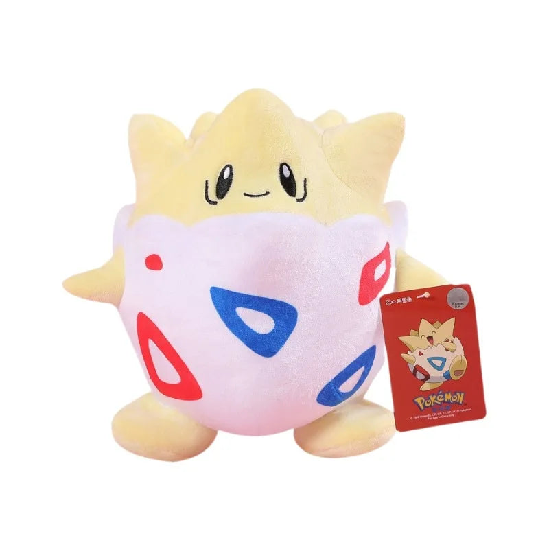 A yellow and white plush doll of Pikachu with red and blue accents, displayed next to its packaging.