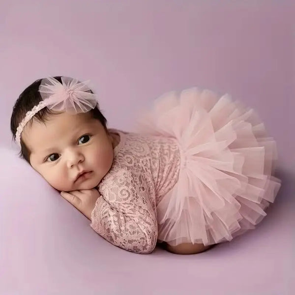 A newborn baby wearing a pink mesh puff sleeve bodysuit and a matching tulle skirt with a pink bow accessory.