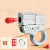 A silver mini shell-ejecting fidget pistol is shown next to various colored and metallic cartridges on a light background.