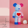 A blue and pink cartoon bear built from LEGO-style blocks, featuring a red heart on its chest.