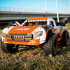 Orange and white high-speed 4WD brushless RC monster truck parked on grass.