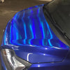 Close-up of a blue car body featuring iridescent holographic chrome vinyl wrap film reflecting light.