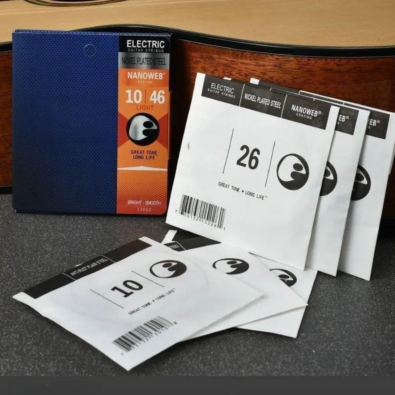 A set of electric guitar strings in a blue box and loose white packaging showing various gauges.