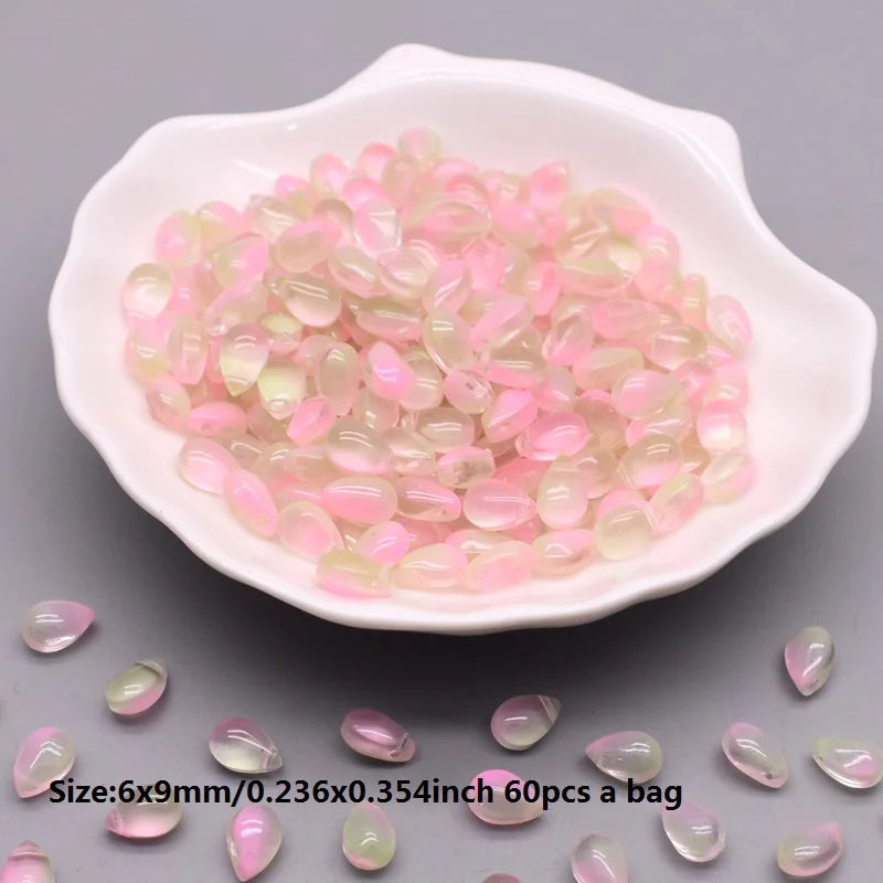 A white dish filled with pink and clear water drop glass beads for jewelry making