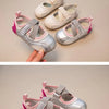 A pair of silver and pink multi-angle display casual slip-on shoes are shown being held by a hand.