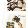 A hand holds a sheet of scrapbook stickers and paper for DIY crafts, with other related materials visible.