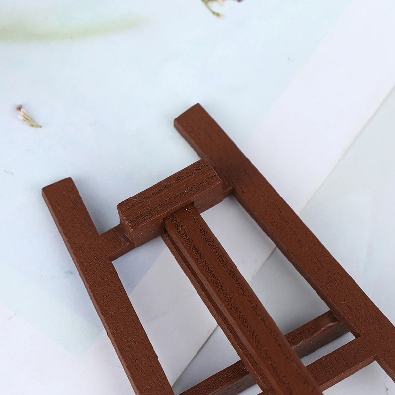 A small wooden artist easel used for a 1:12 dollhouse, featuring brown wood slats.