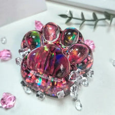 A cluster of iridescent pink and purple acrylic beads and crystals arranged to resemble a cat paw fidget toy