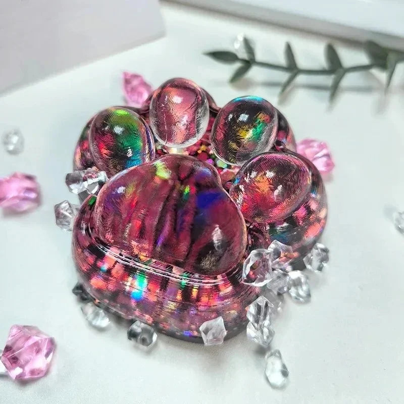 A cluster of iridescent pink and purple acrylic beads and crystals arranged to resemble a cat paw fidget toy