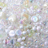 A close-up of colorful iridescent acrylic bow beads and various clear and pearlescent beads for jewelry making
