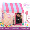 A pink and blue striped foldable kids play tent with a wooden frame and a child inside.