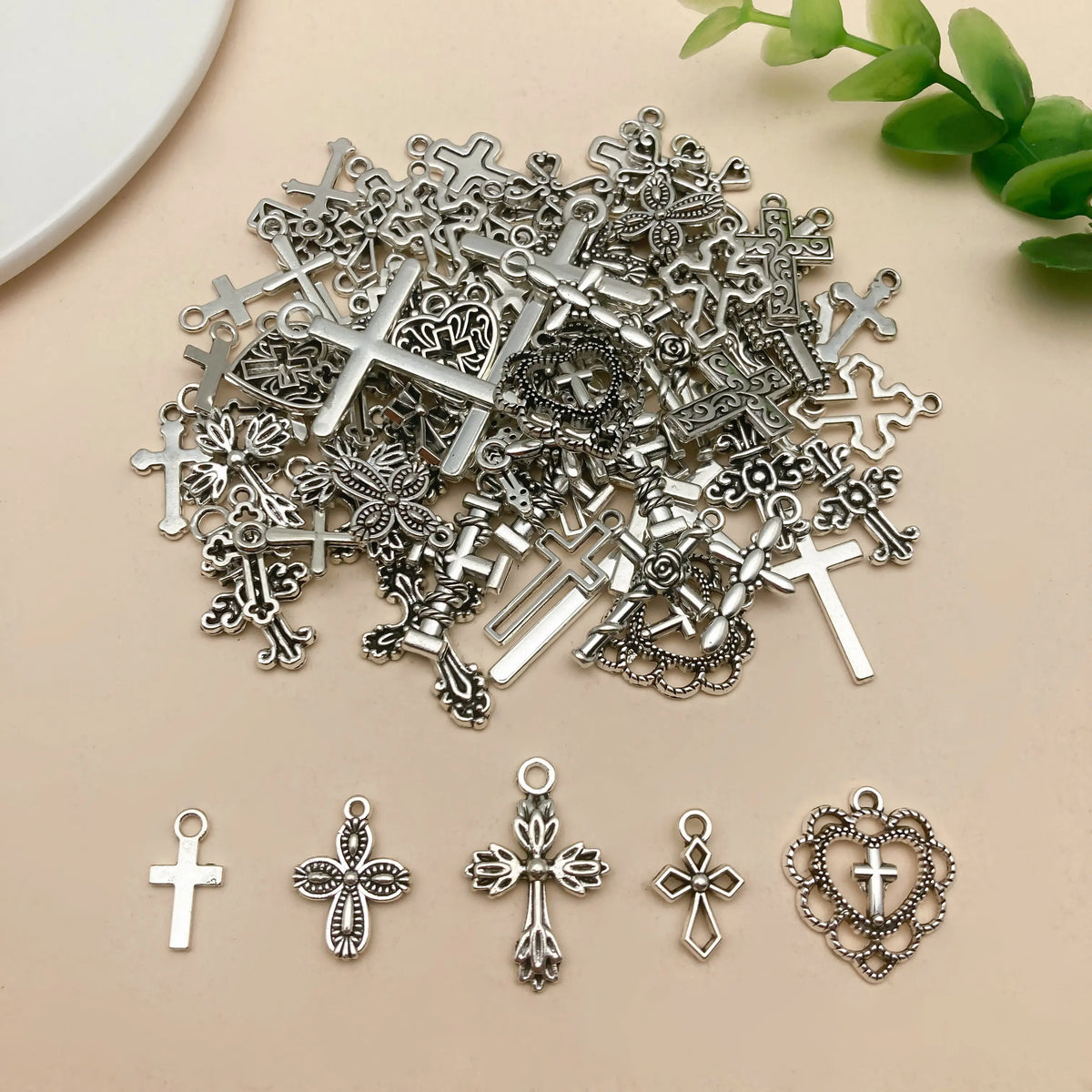 A collection of vintage silver cross charms and pendants for jewelry making scattered on a light background.