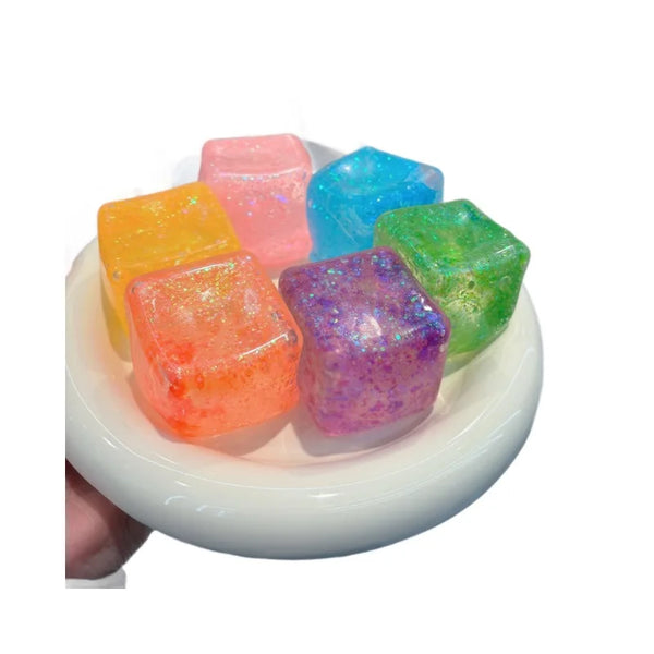 A collection of colorful square stress relief fidget toys in shades of pink, blue, green, and purple resting on a white dish.