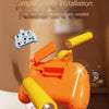 An orange Montessori busy machine with yellow components and an LED light, shown in a close-up on a wooden surface.