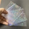 A hand holds a stack of holographic card sleeves featuring colorful stars and glitter patterns.