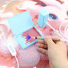 A hand is using an electric diamond painting pen kit with a suction tool to create a design on a pink background.