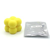 A pile of yellow candle dye chips labeled SUNNY YELLOW next to a clear plastic bag.