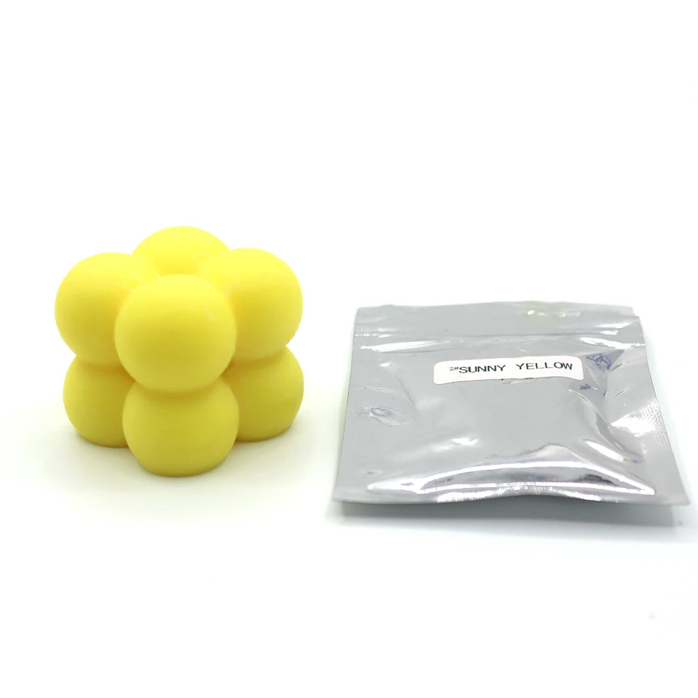 A pile of yellow candle dye chips labeled SUNNY YELLOW next to a clear plastic bag.