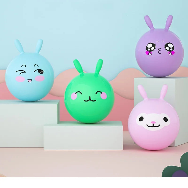 A collection of four purple, green, and pink inflatable hopper balls with handles displayed on white pedestals.