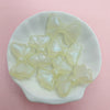 A collection of translucent pale yellow shimmer mermaid bowknot beads displayed in a white dish.