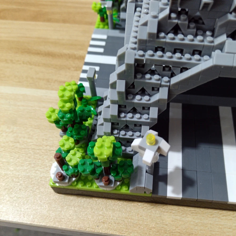 A model of the Eiffel Tower built from gray LEGO-style blocks with green foliage on a wooden surface.
