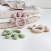 A collection of silicone baby teethers in pink and green resting on a soft, textured cloth.