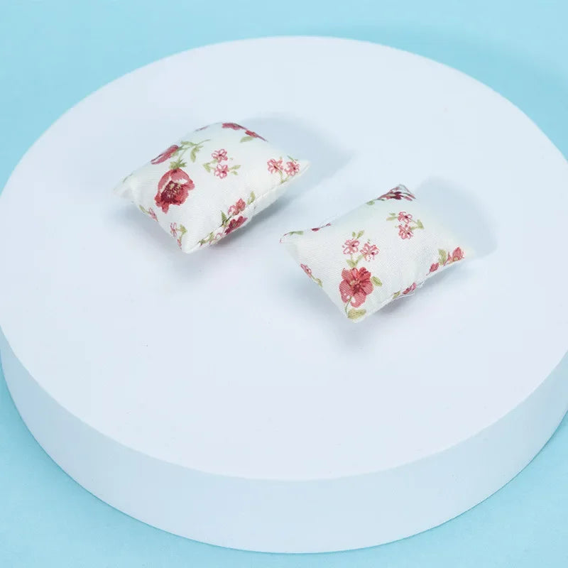 A small floral patterned fabric pillow resting on a white circular surface.