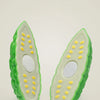 A pair of green pretend play fruit and vegetable cutting set pieces with yellow dots and white filling.
