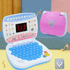 A pink and blue kids interactive learning laptop toy with a keyboard and accessories is shown on a light yellow surface.