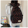 Un sac à dos noir avec motif nœud rouge porté par une personne en pull gris clair.