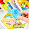 A hand holds a wooden 3D jigsaw puzzle featuring various colorful dinosaur and animal shapes.