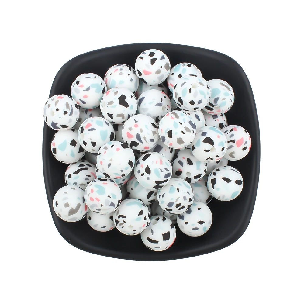 A black bowl filled with small white and pink printed silicone beads for jewelry making.