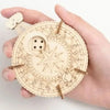 A hand holds a circular wooden puzzle kit with intricate lines and a small wooden piece.