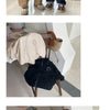 A black hooded zip-up jacket with a white letter print is displayed on a wooden chair.
